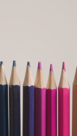 Vertical-Video-Studio-Shot-Of-Multi-Coloured-Pencils-In-A-Line-On-White-Background-